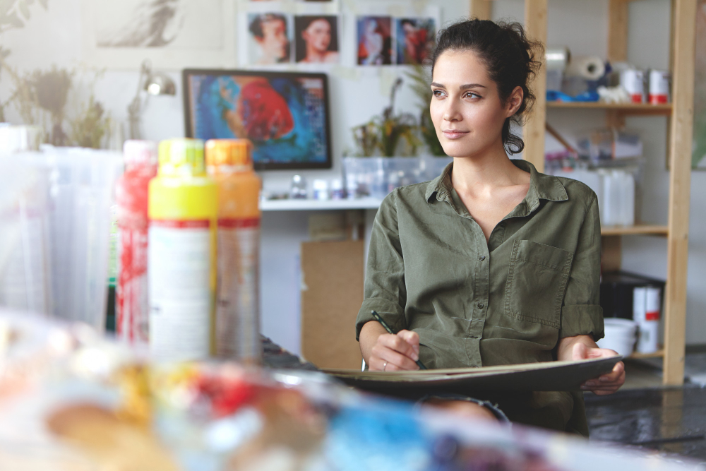 joven mujer sentada en un taller moderno y trabajando en ideas de negocio